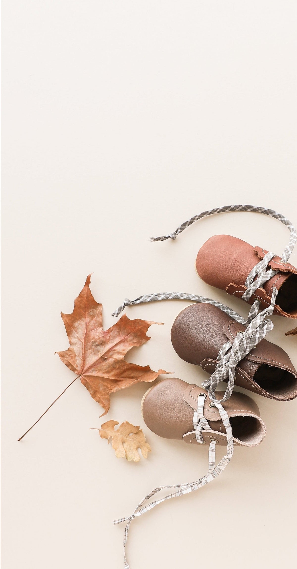 baby boots lined up with plaid laces and fall leaves