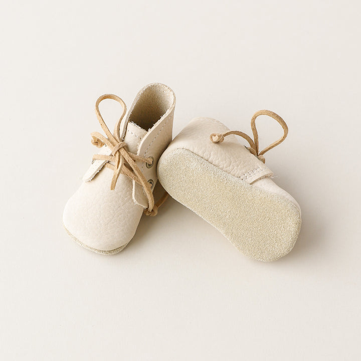 Soft soled baby boots with zero drop suede soles. One shoe angled on its side.