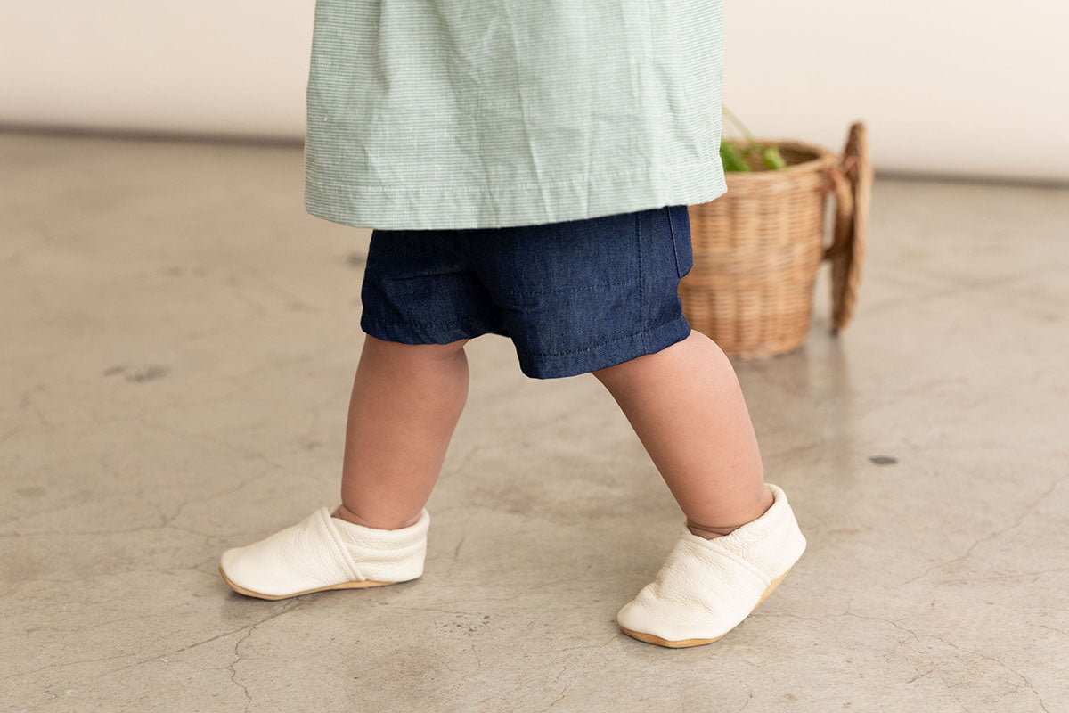 Why soft soles? Little girl walking in white slip-on baby shoes