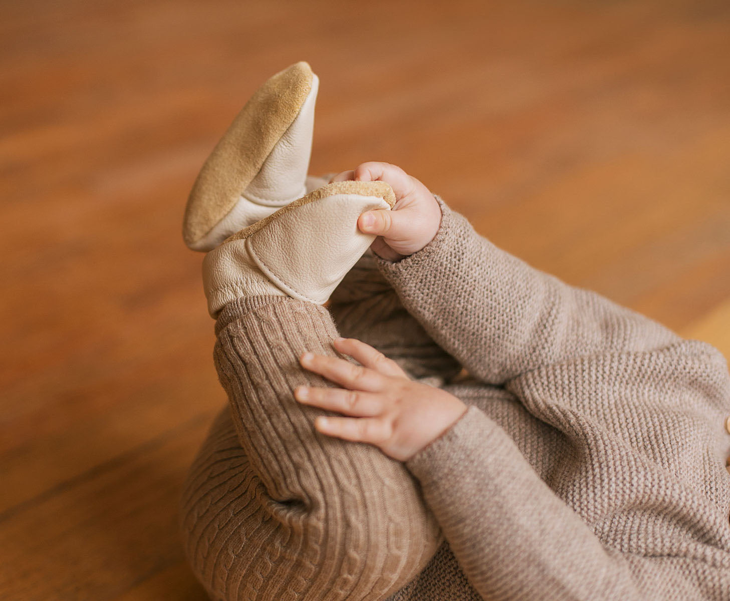 Cream leather baby moccasins on baby feet