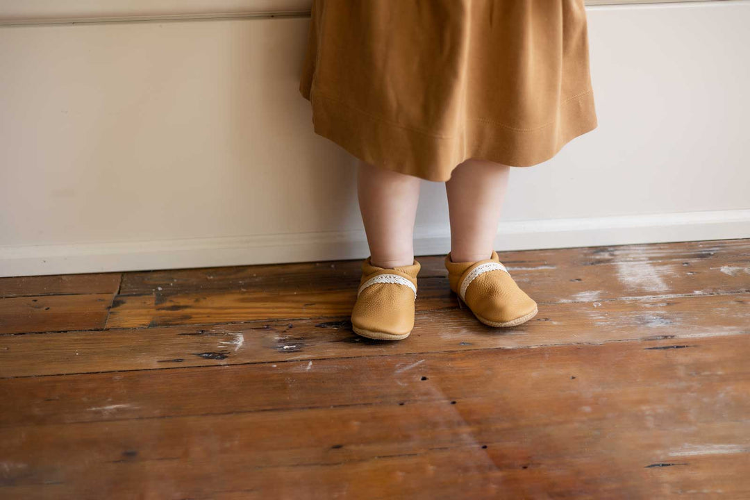 toddler girl wearing slip on shoes by window