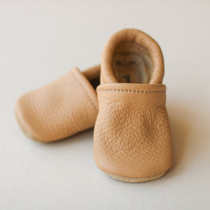 light brown leather gender neutral baby slip-on shoes. One agreed in front and top of other