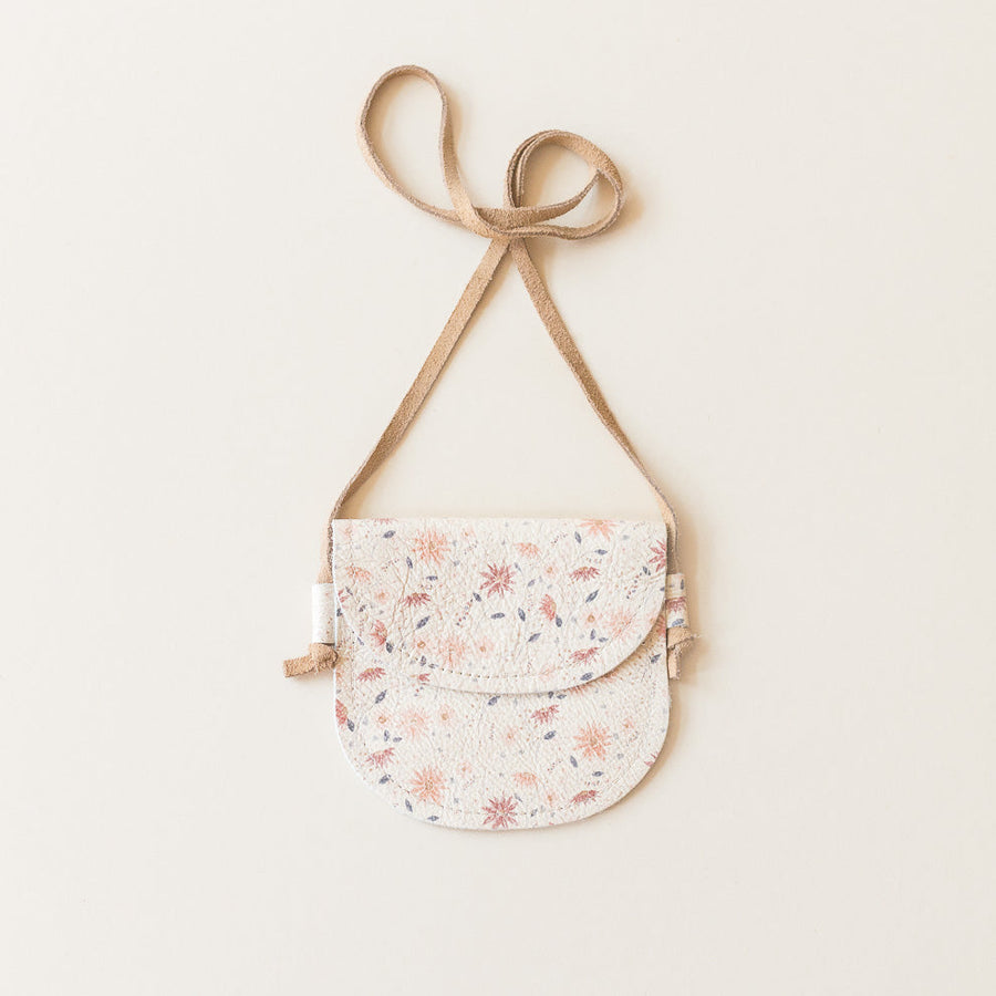 Floral-patterned crossbody bag with a beige strap on a light background
