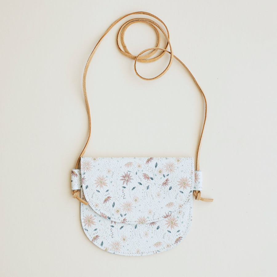 Small floral-patterned little girls purse with a strap on a light beige background