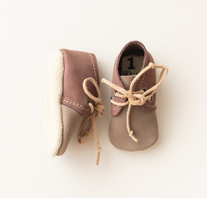 A pair of baby oxfords in brown and beige suede with beige laces, shown from the side and top on a clean white background.