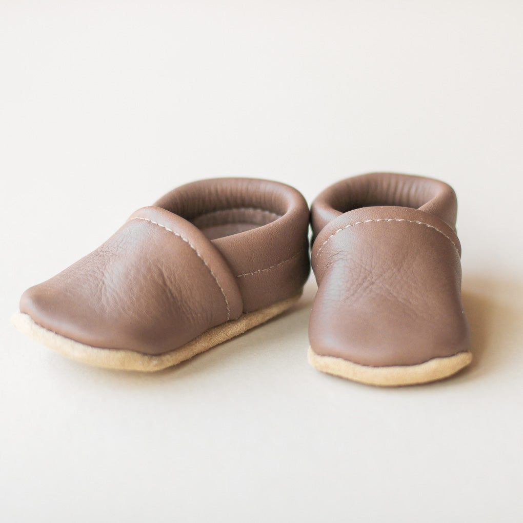 Pair of gray leather baby shoes on a light background