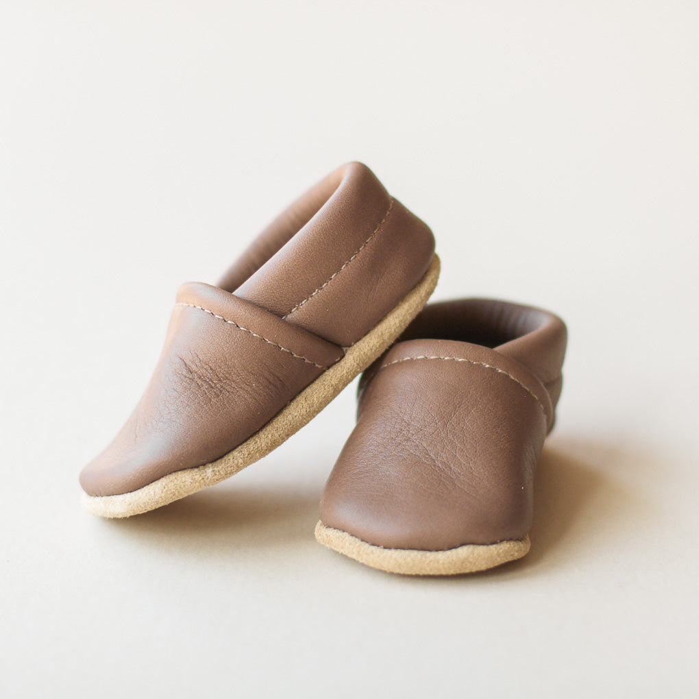 Pair of dark gray leather baby shoes on a light background
