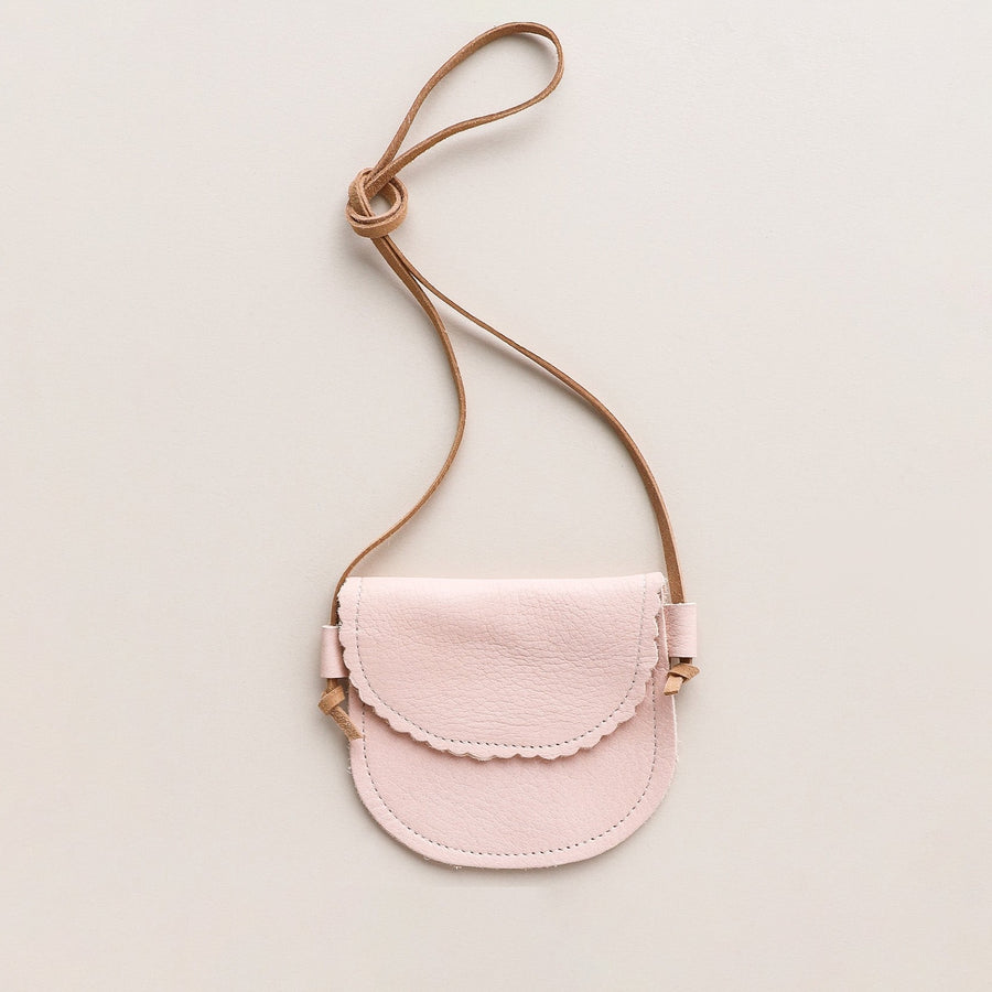 light pink leather little girls purse with scalloped edge flap. product on beige background.