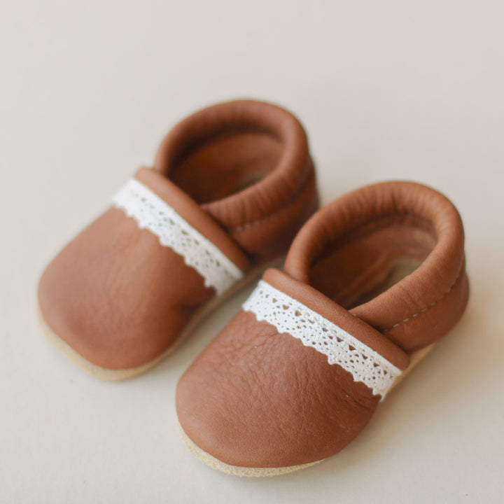 product picture of medium brown leather baby girl slip-on shoes with lace trim. soft suede soles.