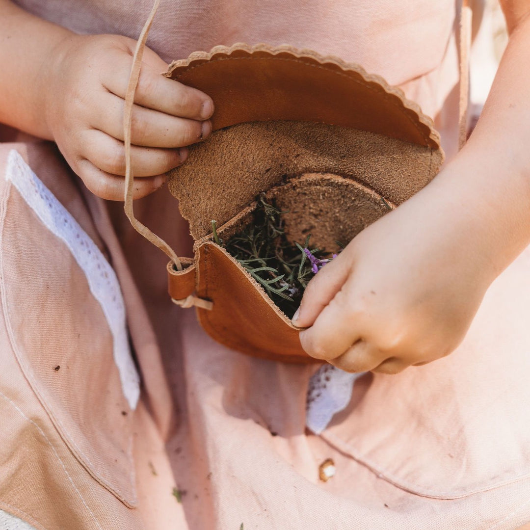 Toddler hands opening her leather cross-body purse to show flowers. 