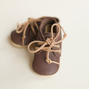 dark brown leather baby oxfords. one angled in front of the other. sued laces.