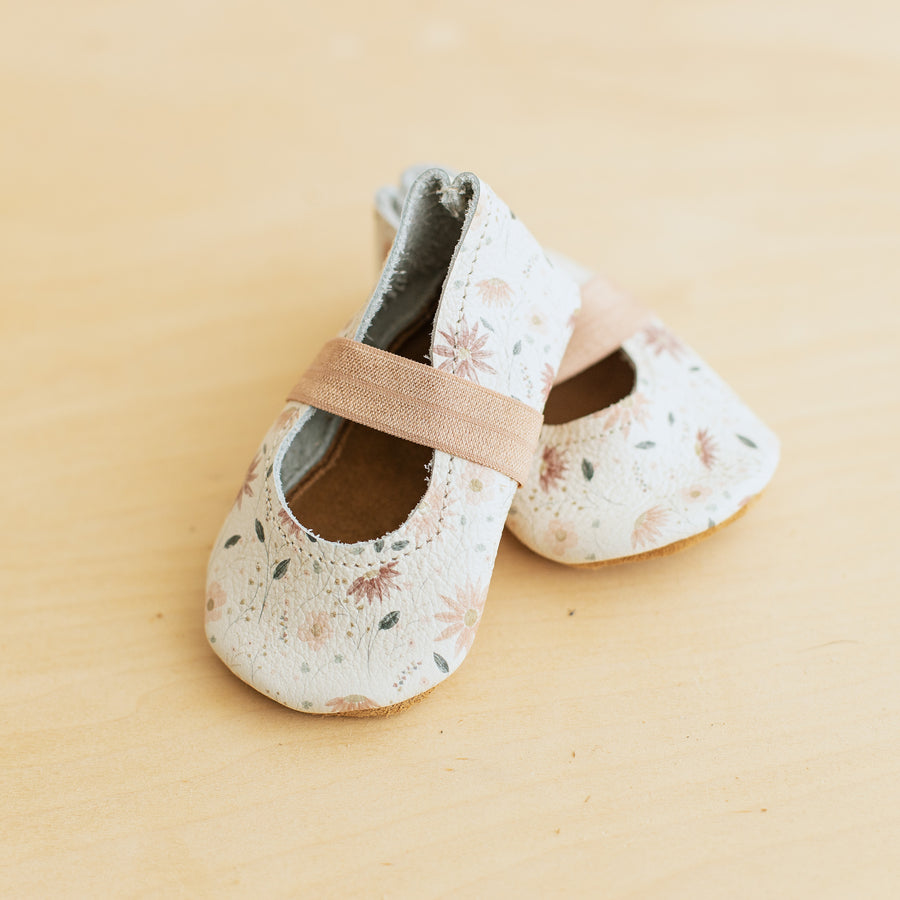 White background with pink floral leather baby ballet flats with soft soles. 