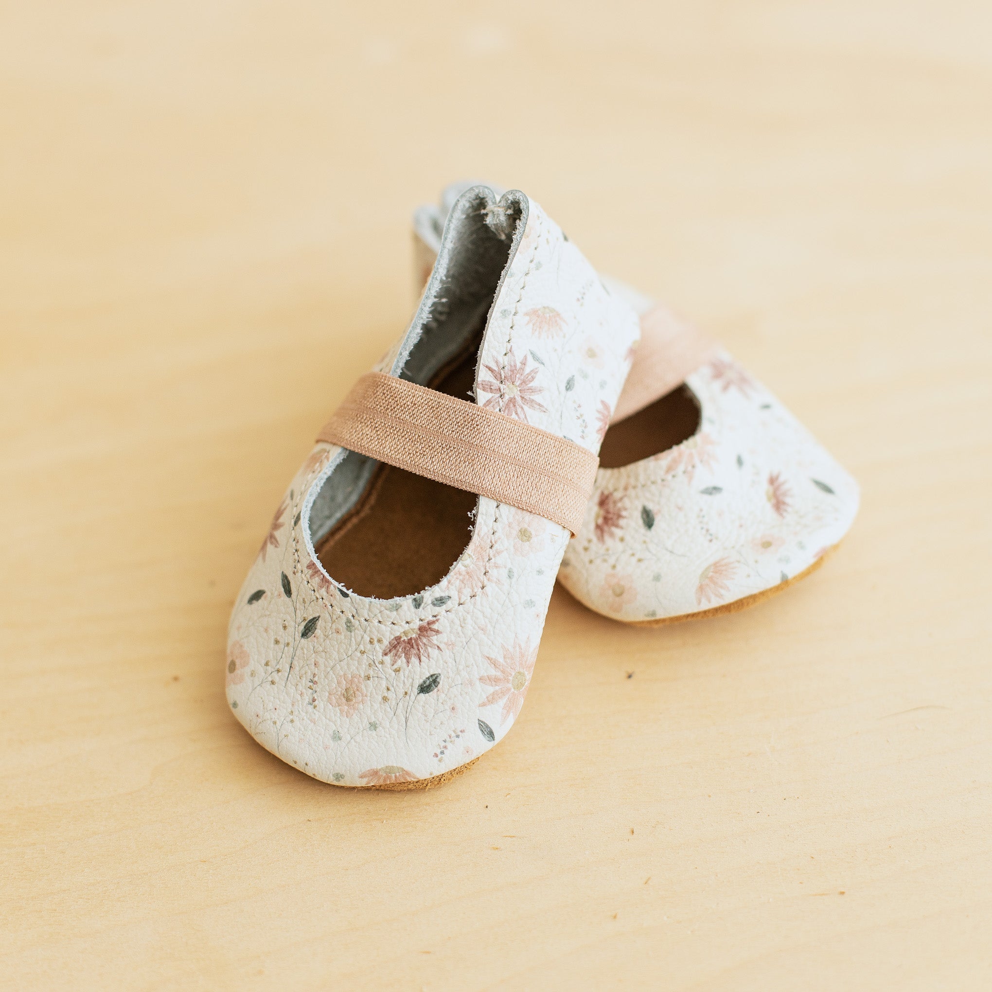White background with pink floral leather baby ballet flats with soft soles. 