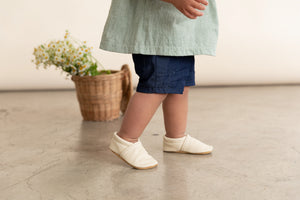 cream leather slip on baby shoes in a gender neutral style. Shown on girl