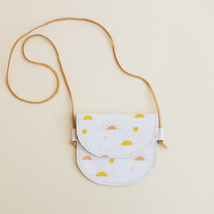 Product image of toddler cross-body  bag in sun print. Toddler girl purse with yellow and pink suns. Cream photo background